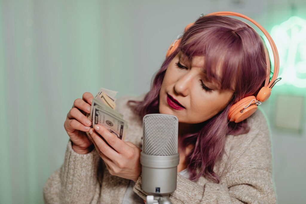 Woman wearing headphones recording ASMR with cash and microphone indoors.